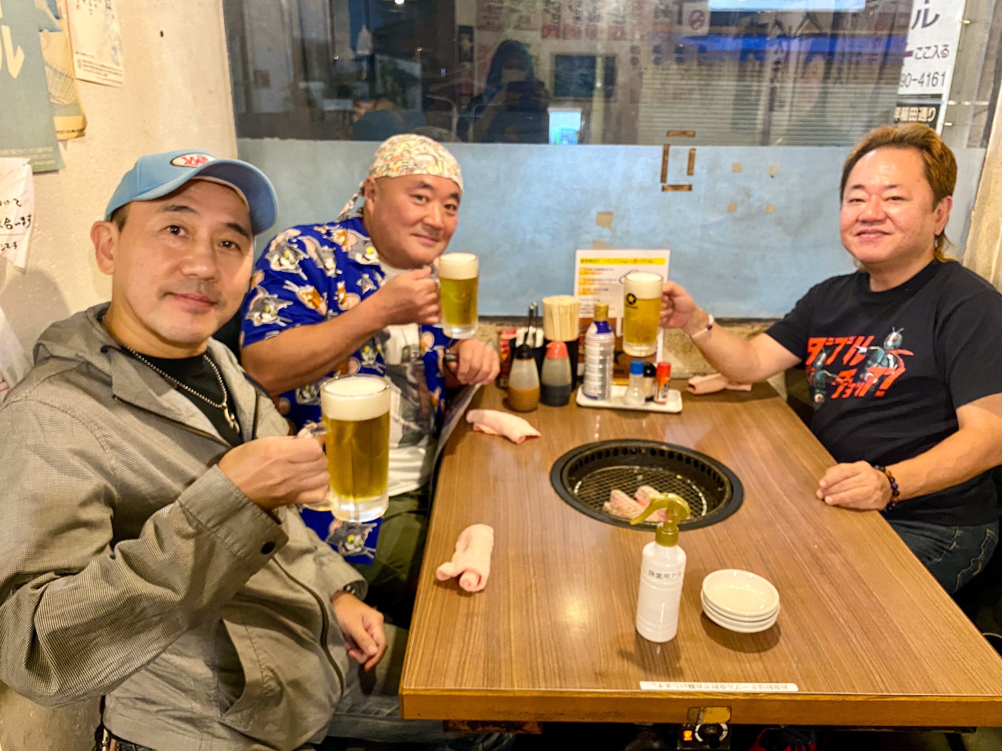 Nakagawa e dois amigos brindando com canecas de cerveja num izakaya
